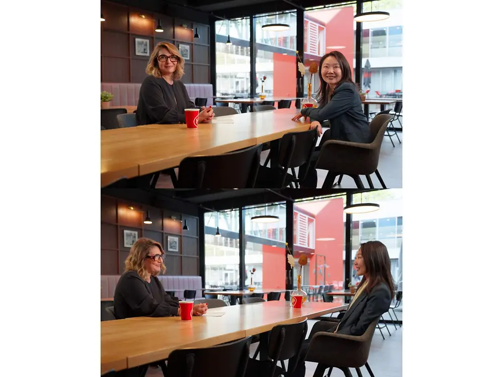 Two participants sit across from each other at a table and talk in a café setting.