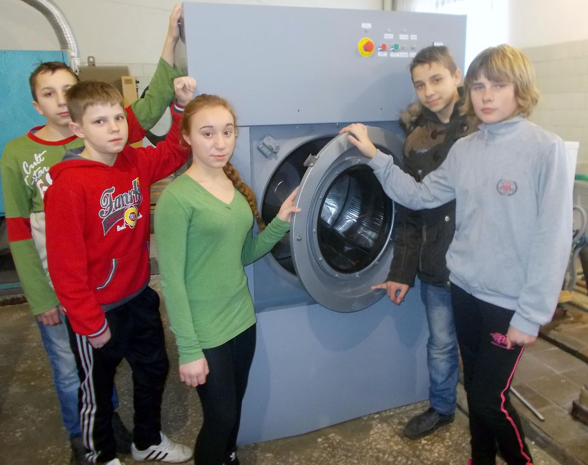 Foster children pose with the donated industrial washing machine