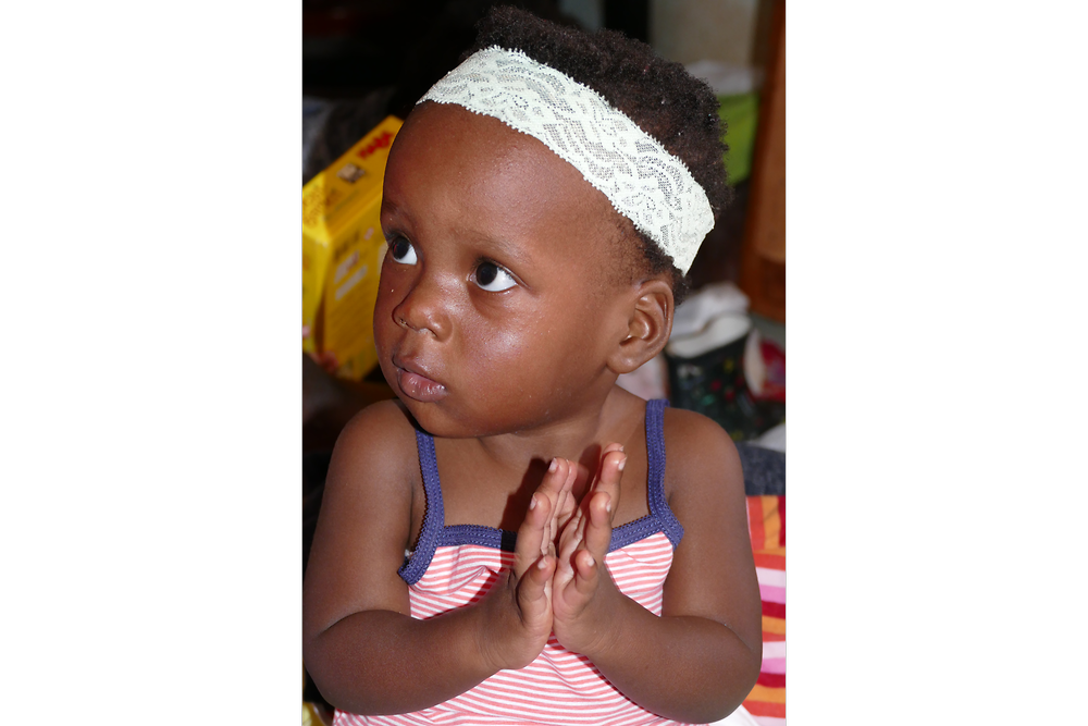 Little Merci listens to the caregivers chanting 
